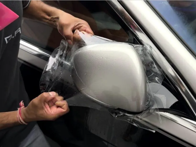 Foto real de PPF sendo aplicado em retrovisor prateado
